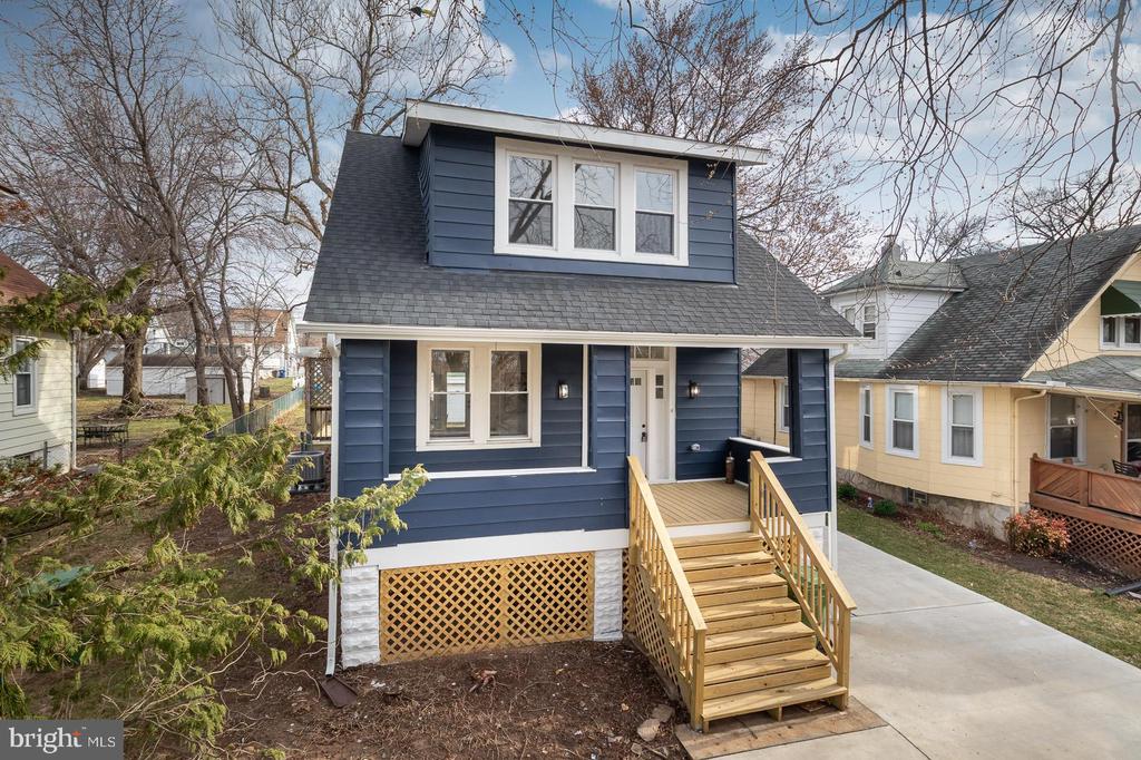 Blue two-story house with a steep roof, dormer windows, and wooden steps to the covered porch.