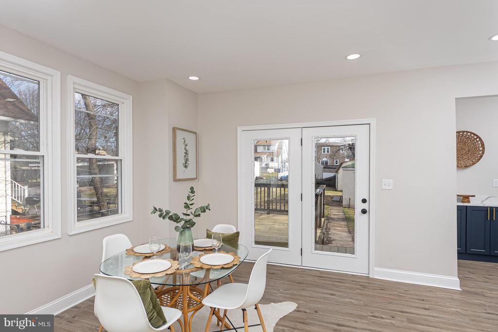 Dining area with a round glass table beside windows and glass doors to a deck.