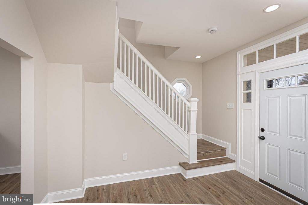 Entryway with a white front door, sidelights, and a staircase with white railing.