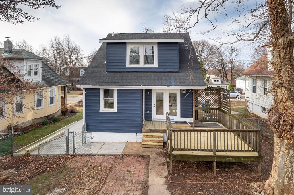 Blue two-story house with a roof dormer and raised wooden deck.