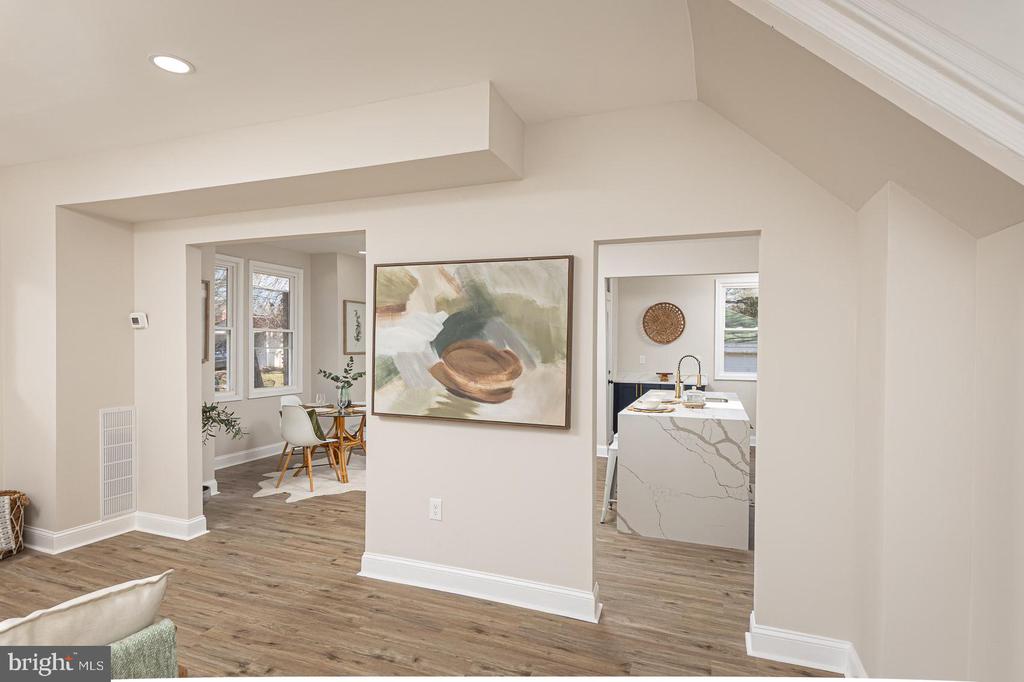 Open living area with wood-look floors, an abstract painting, and views into the dining nook and kitchen.