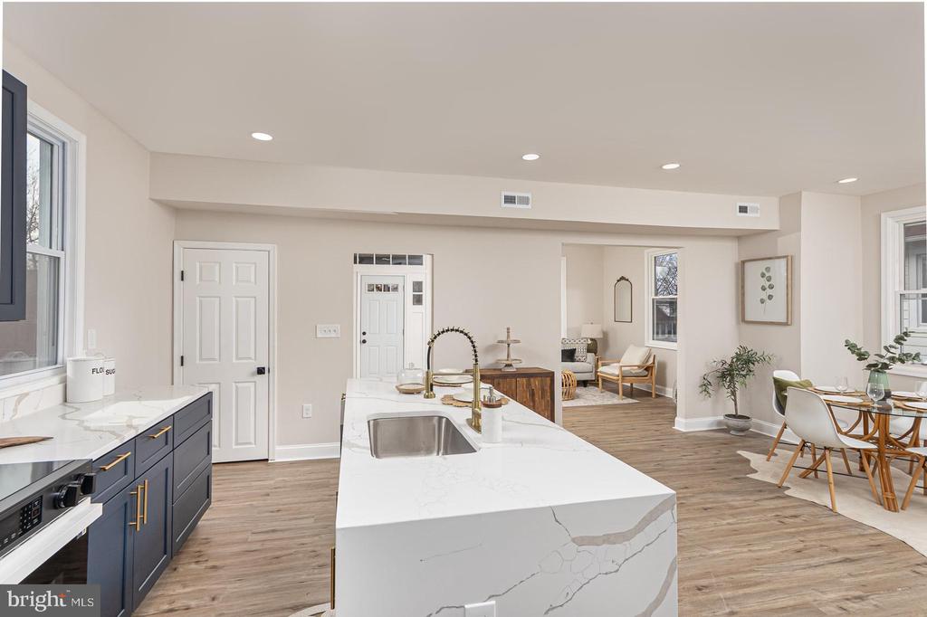 Open kitchen with a marble island, navy cabinets, and adjoining furnished dining area.
