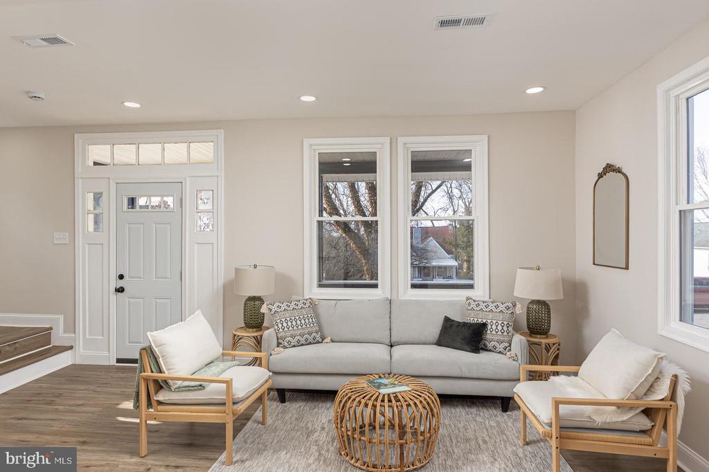 Staged living room with a gray sofa, woven coffee table, and white paneled entry door.