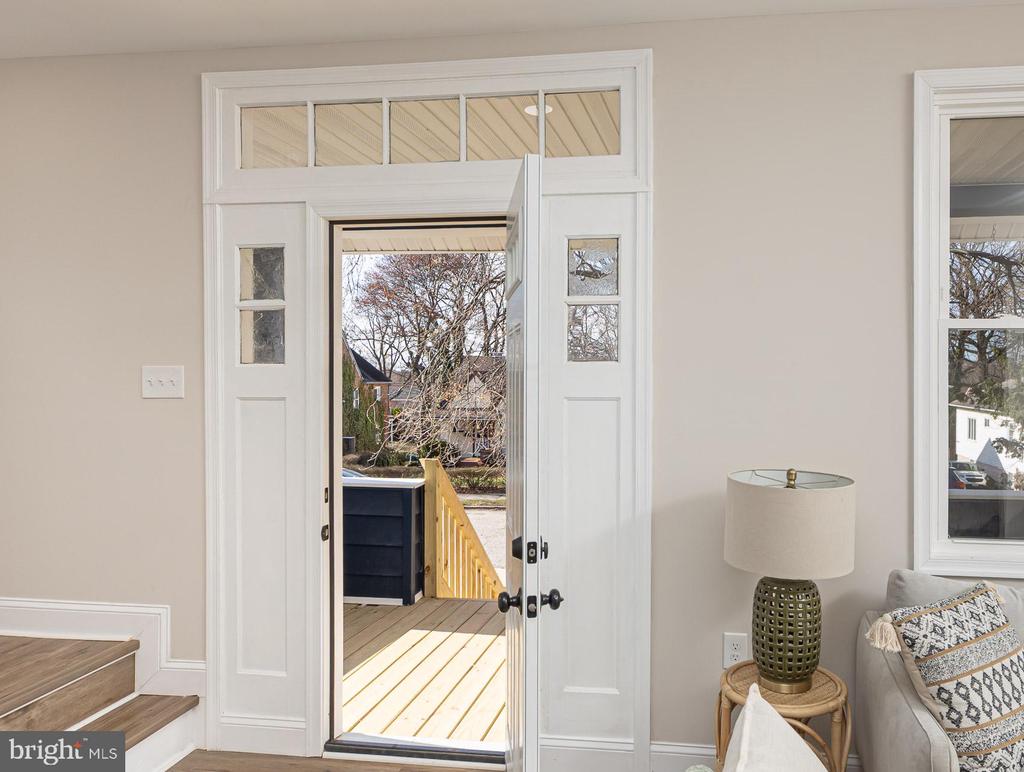 Entry foyer with an open white front door leading to a sunlit wooden porch.