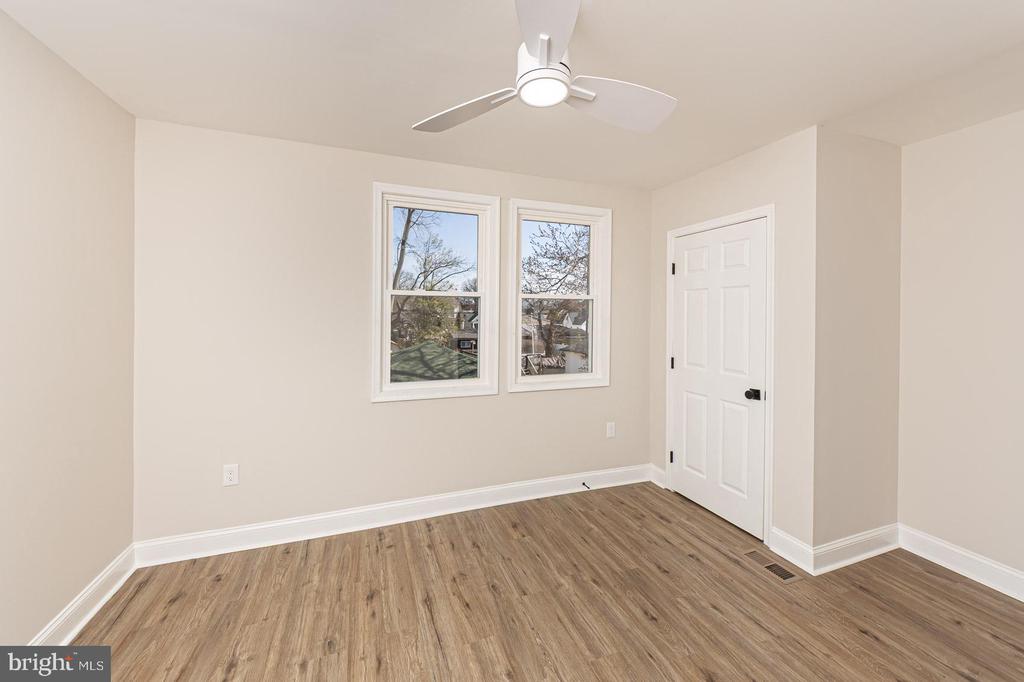Empty room with wood-look flooring, two windows, and a ceiling fan.