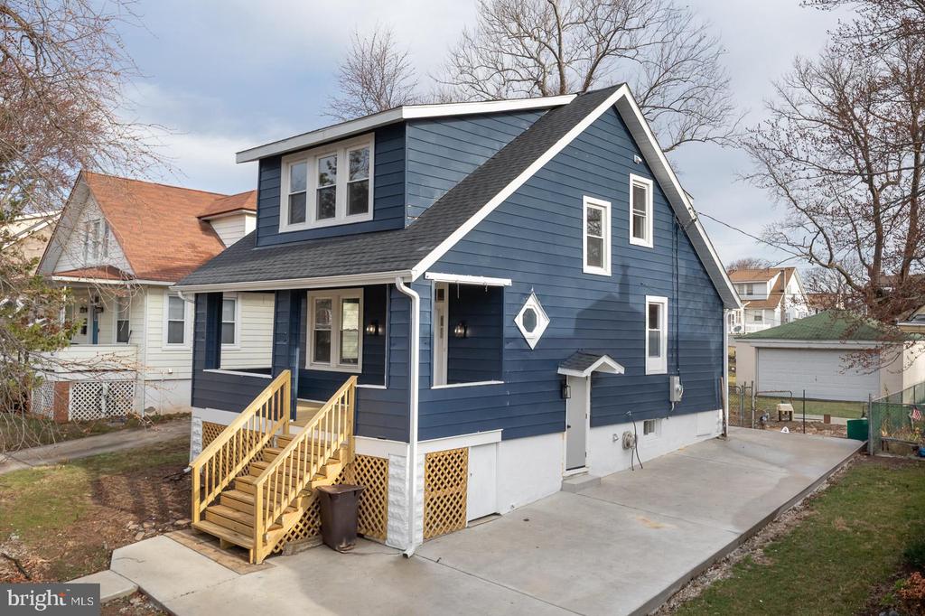 Blue-sided house with white trim, wooden steps, and a wide concrete driveway.