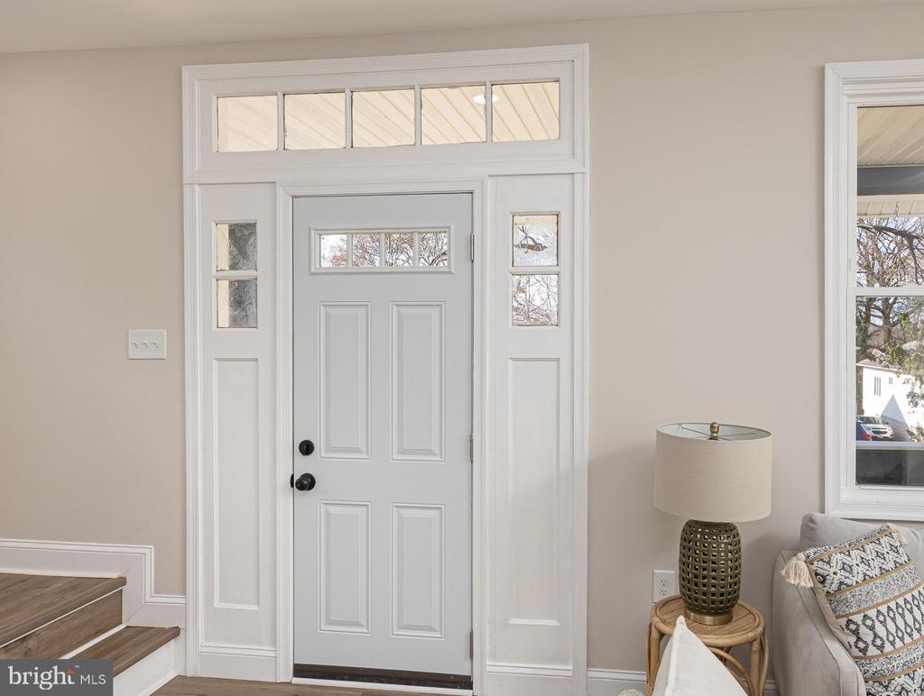 Entryway with a gray front door, glass transom and sidelights, and a staircase.