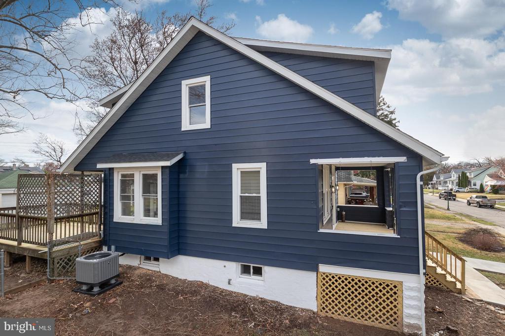 Blue-sided rear of the home with white trim, a wooden deck, and a large open window.