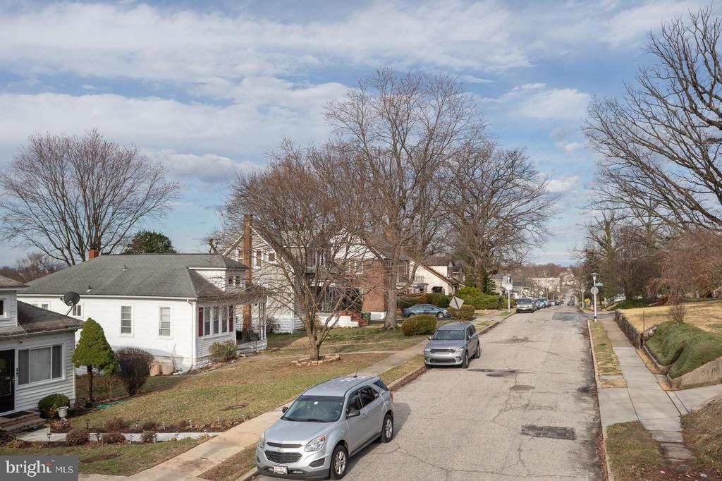 Residential street lined with detached homes, bare trees, and parked cars.