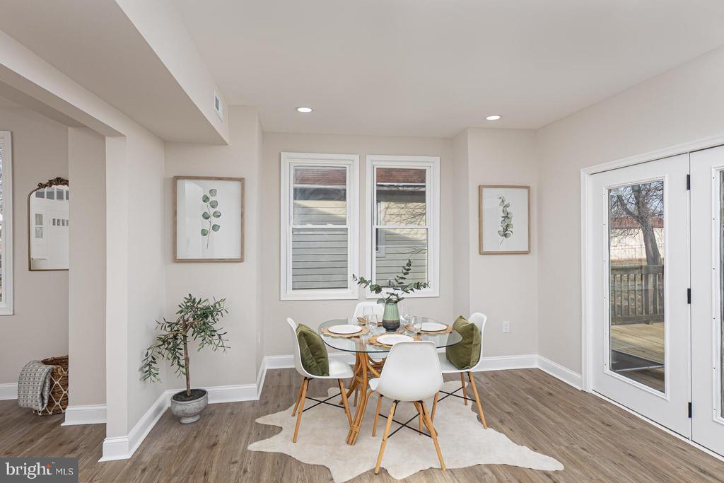 Dining area with a round glass table, white chairs, and glass doors to a deck.