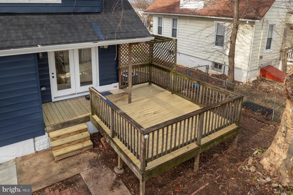 Raised wooden deck with lattice panels and steps beside a blue-sided house.