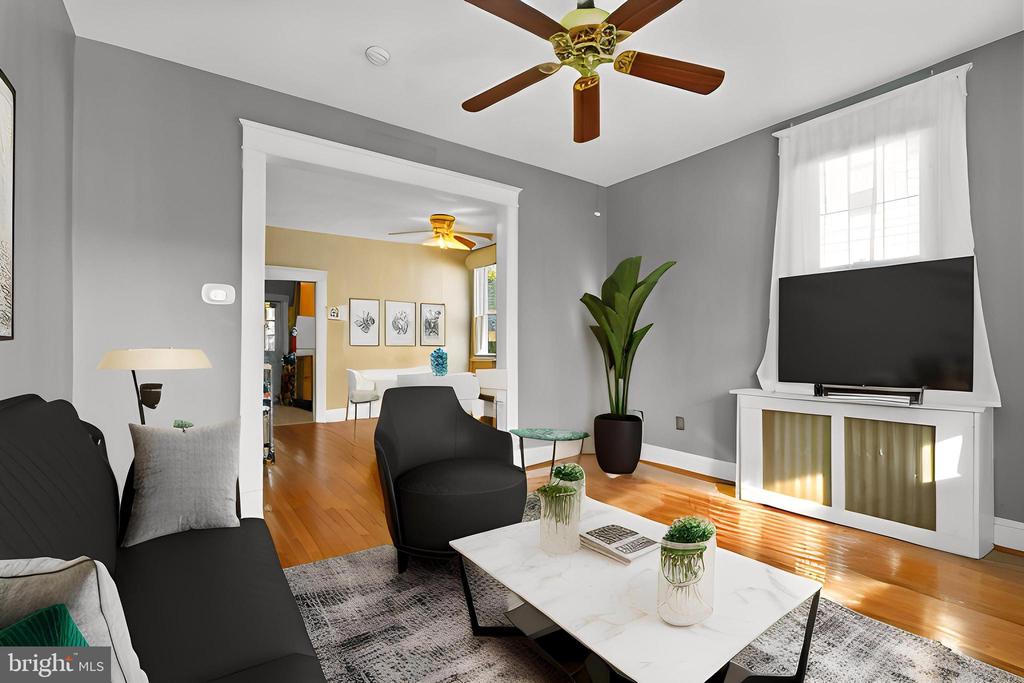 Furnished living room with a black sofa, marble coffee table, and TV above a fireplace.
