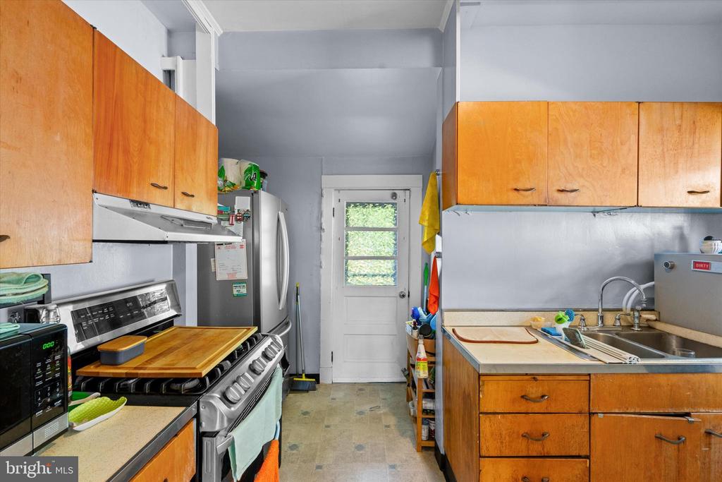 Kitchen with orange wood cabinets, stainless-steel appliances, and a glass-paneled back door.