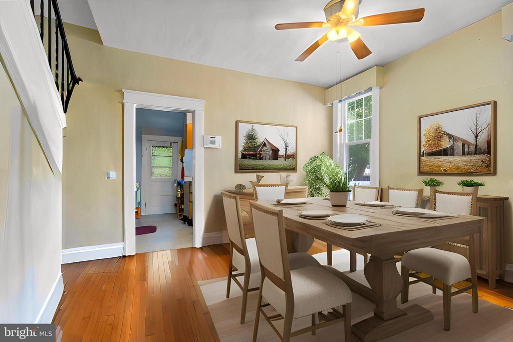 Dining room with a large wooden table, upholstered chairs, hardwood floors, and a ceiling fan.
