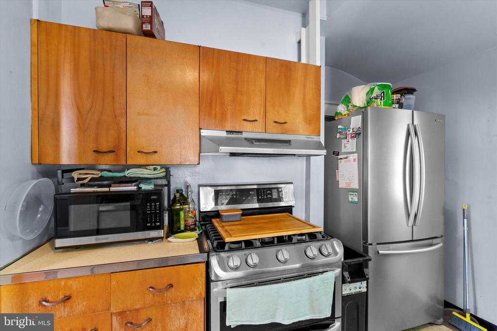Kitchen with wood cabinets, a gas range, microwave and stainless steel refrigerator.