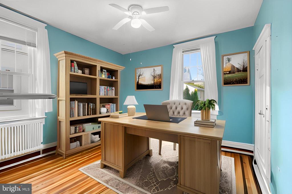 Furnished home office with turquoise walls, a large wooden desk, and a built-in-style bookcase.