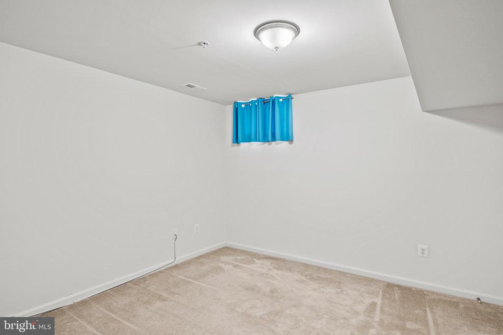 Empty carpeted room with white walls, blue curtains, and a ceiling light.