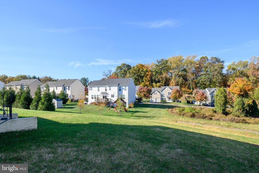 Neighborhood green with detached homes, a small playground, and autumn trees.