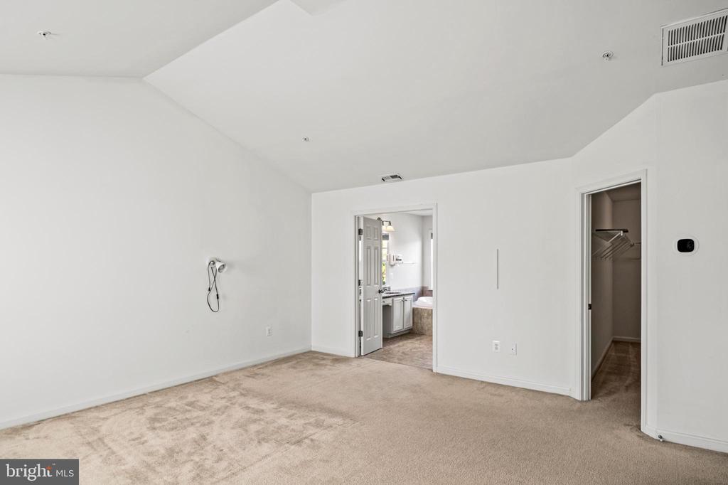 Vacant bedroom with beige carpet, a walk-in closet, and an ensuite bathroom.