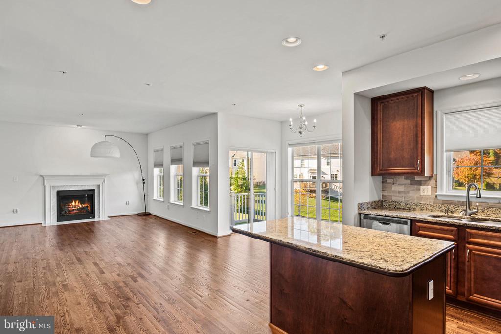 Open-plan kitchen and living room with a granite island, hardwood floors, and a fireplace.