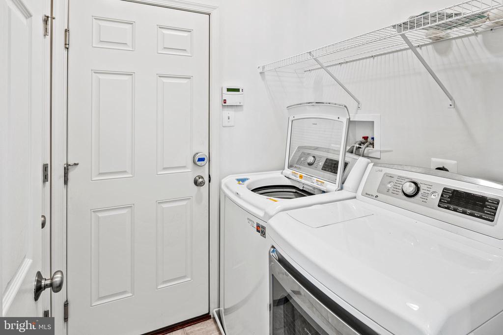 Laundry room with washer, dryer, overhead wire shelving, and a keypad lock on the door.