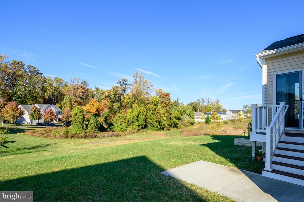 Backyard lawn and autumn tree line beside the house, with neighboring homes in the distance.