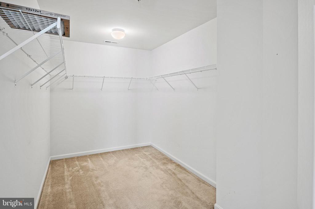 Empty walk-in closet with beige carpet and white wire shelving.