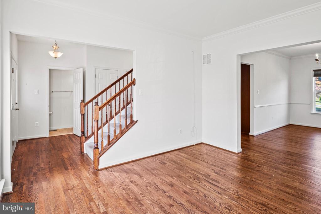 Vacant interior with hardwood floors and a wooden staircase beside the entry hall.