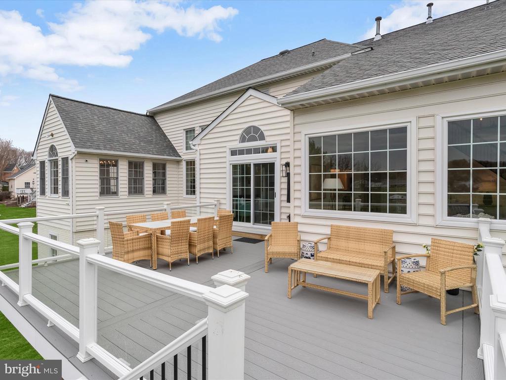 House with a spacious furnished deck, white railings, and large windows.