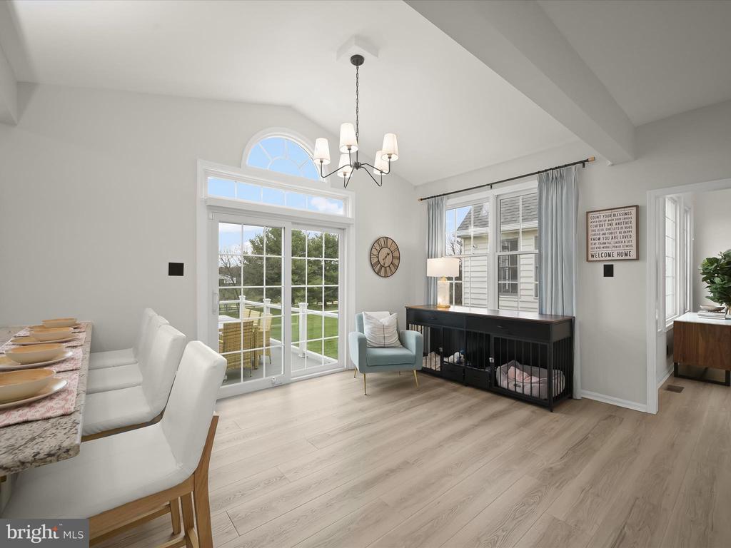 Dining area with vaulted ceiling, tall windows, and a black console with a pet crate.