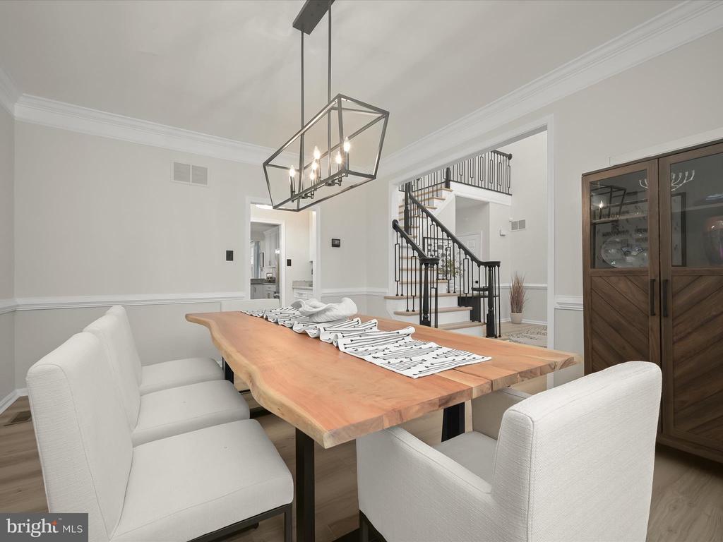 Dining room with a live-edge wood table, white chairs, and a staircase with black railings.