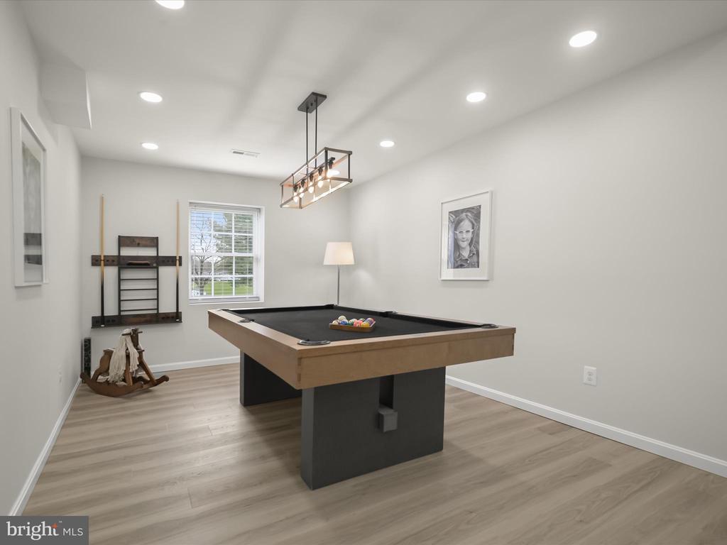 Game room with a black-and-wood pool table and wall-mounted cue storage.