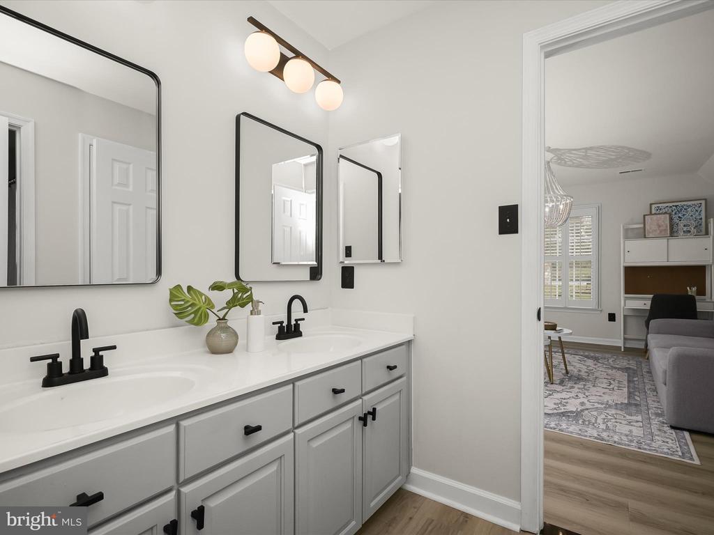 Bathroom with a long double-sink vanity, gray cabinets, black faucets, and three mirrors.