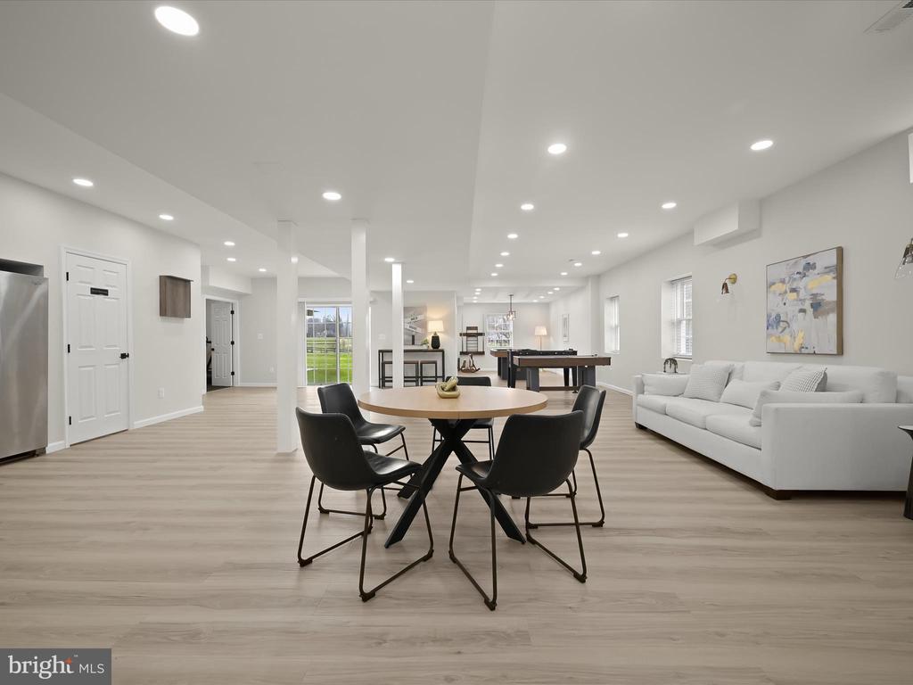 Open living and recreation room with a round dining table, white sectional, and pool table.