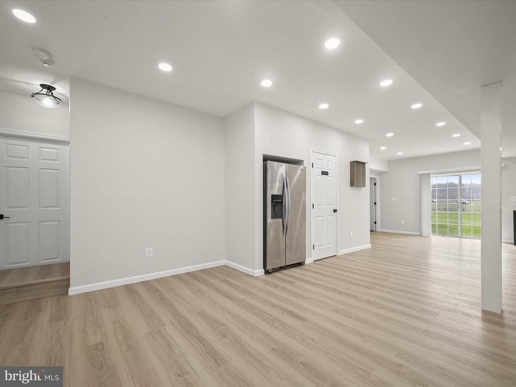 Vacant open-plan kitchen and living area with a stainless steel refrigerator and sliding glass doors to the yard.