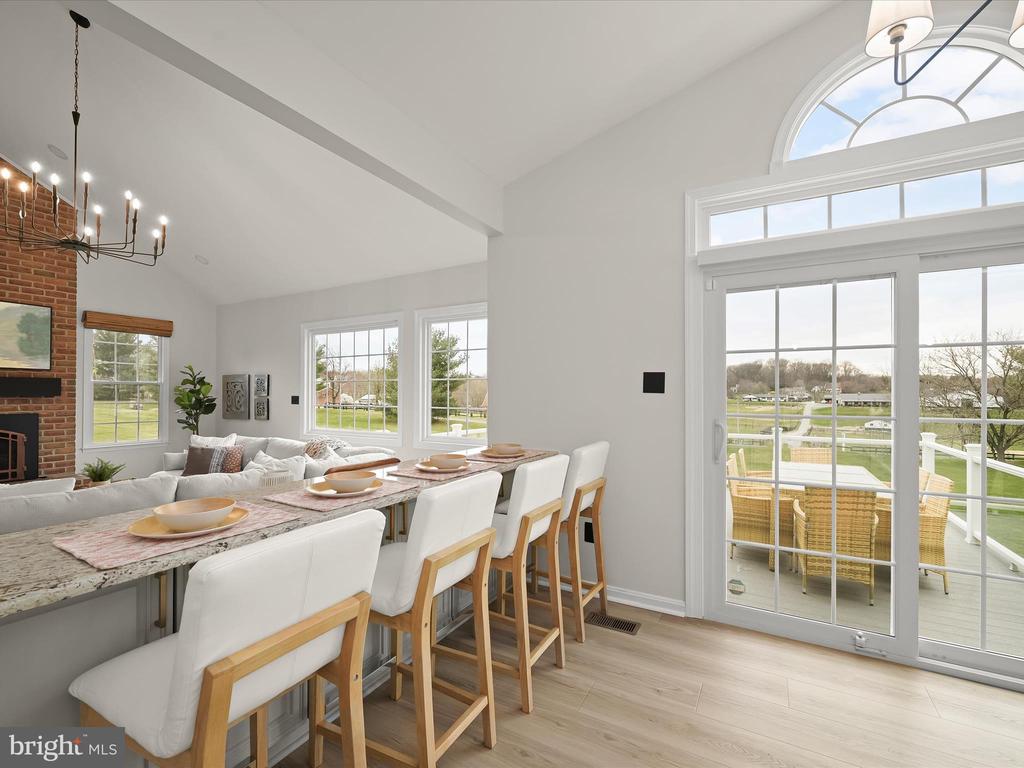 Dining area with a stone-topped island, brick fireplace, and glass doors opening to a deck.