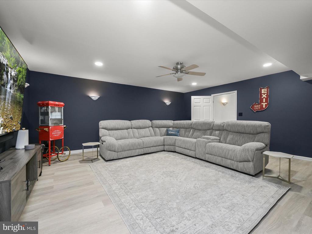 Furnished recreation room with a gray sectional, waterfall display, and red popcorn machine.