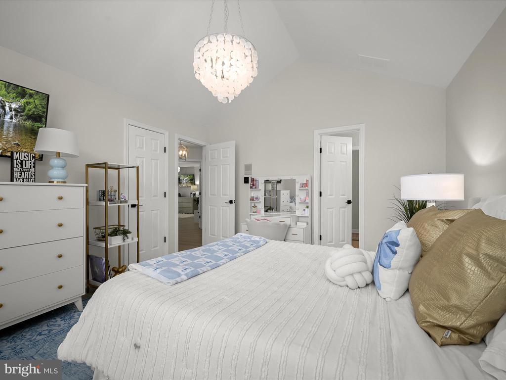 Staged bedroom with a white bed, blue accents, and a hanging crystal light.