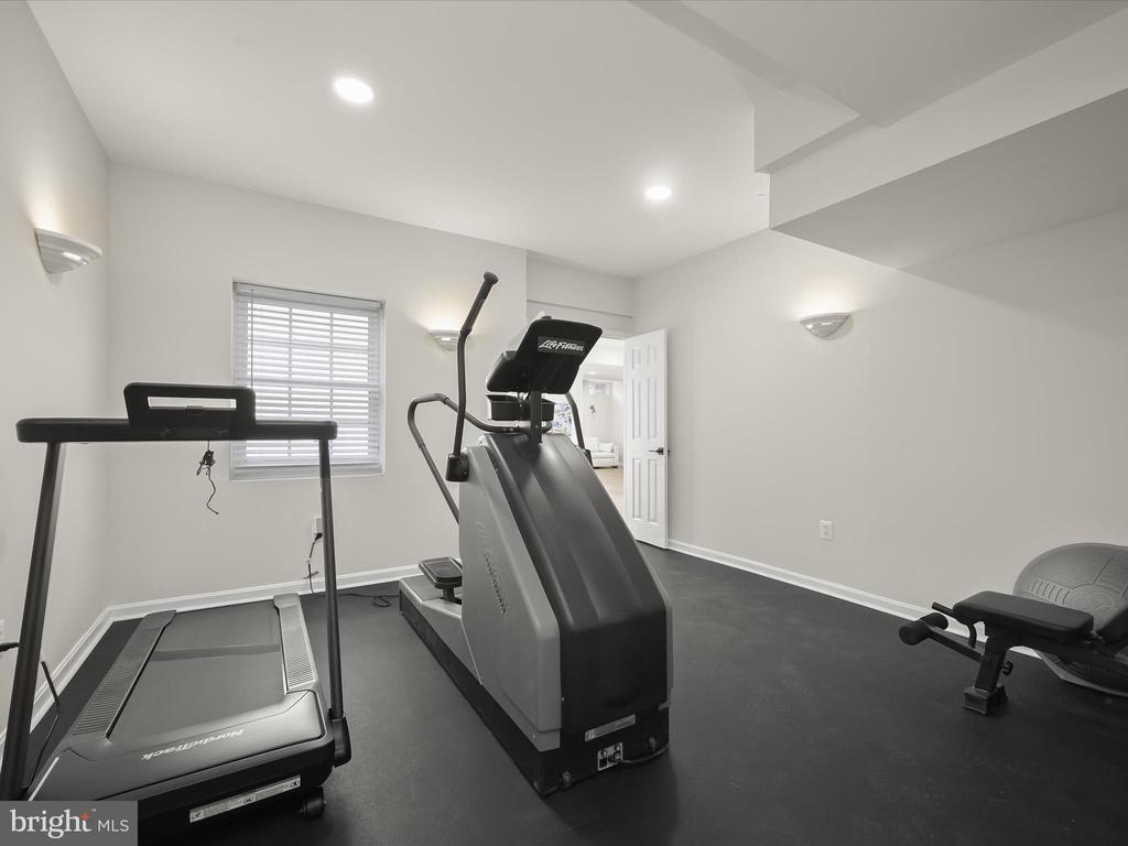 Home exercise room with a treadmill, elliptical machine, and weight bench.