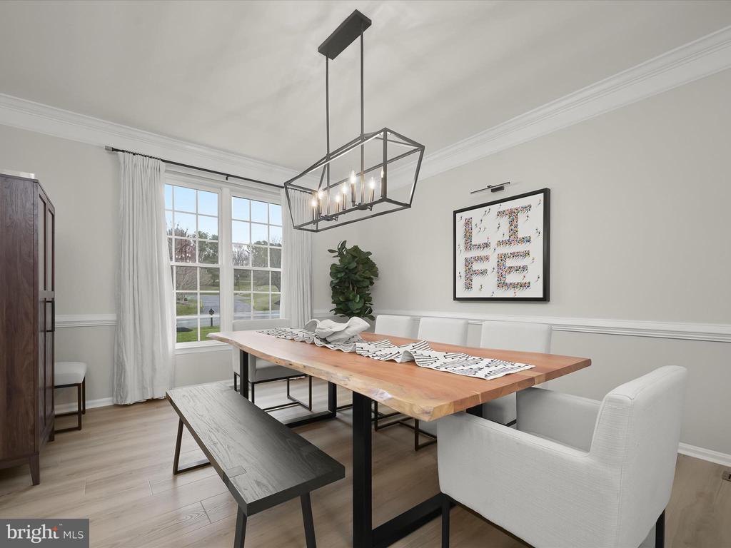 Dining room with a long wood table, dark bench, white chairs, and a geometric chandelier.