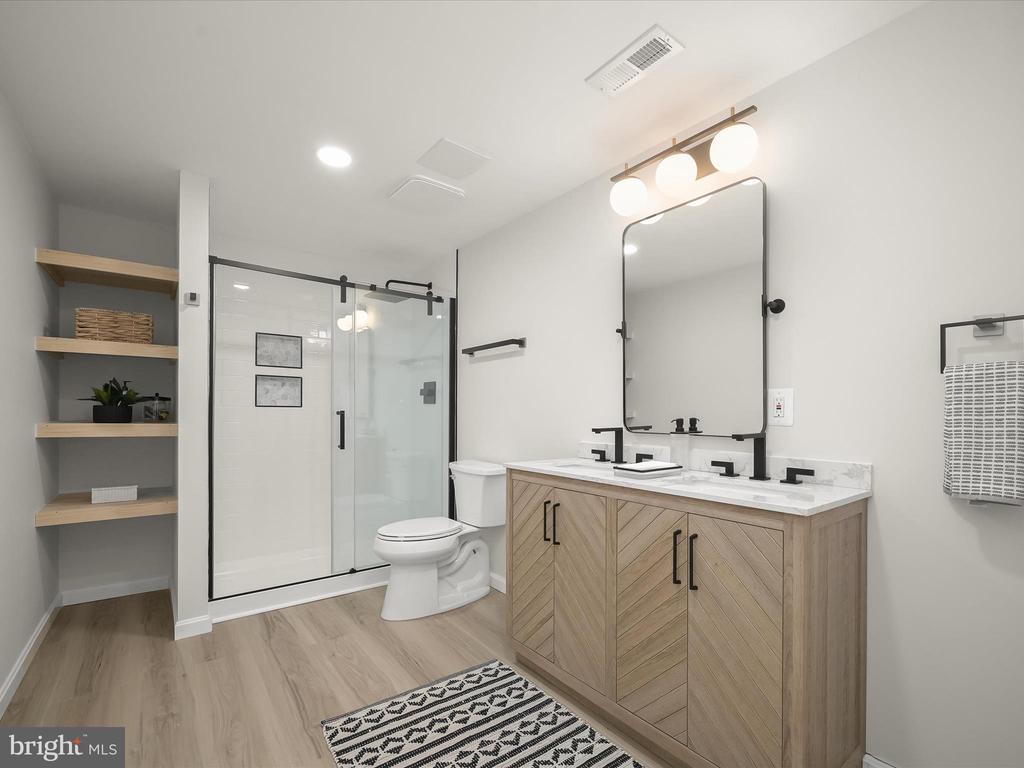 Bathroom with a glass shower, light wood double vanity, and built-in open shelves.