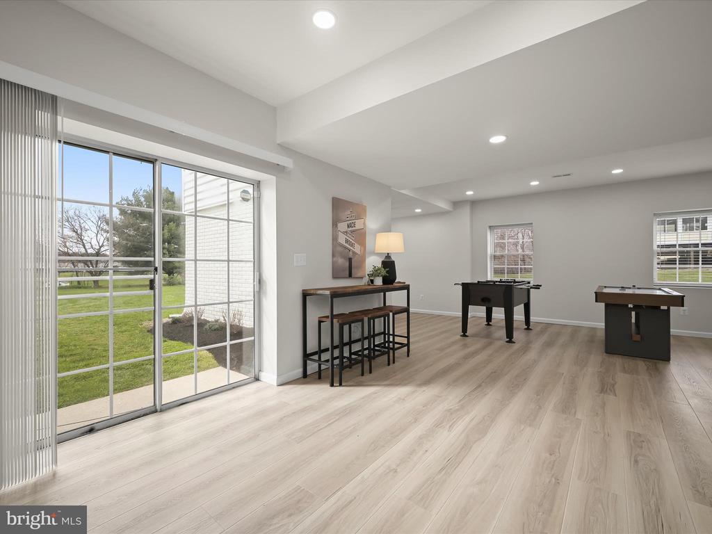 Game room with foosball and pool tables, pale flooring, and a sliding glass door to the lawn.