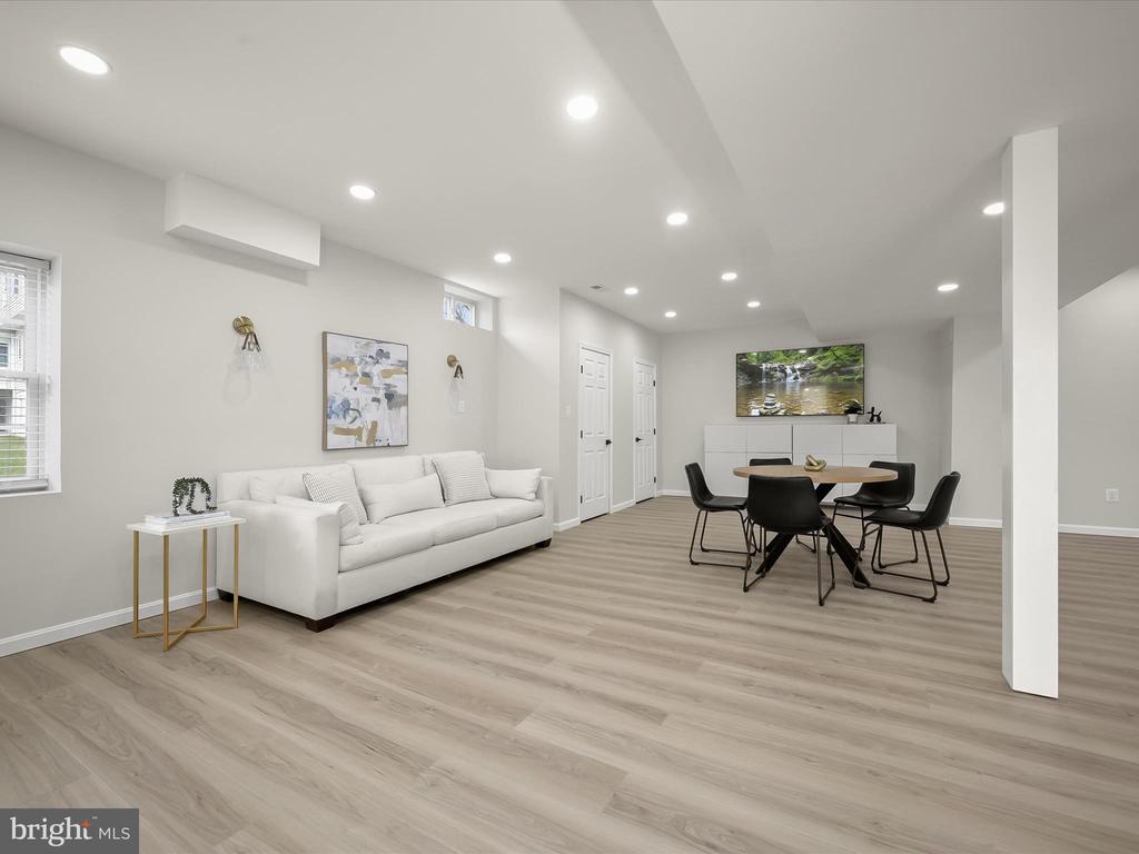 Open-plan living and dining area with a white sofa, round table, and light wood-look flooring.