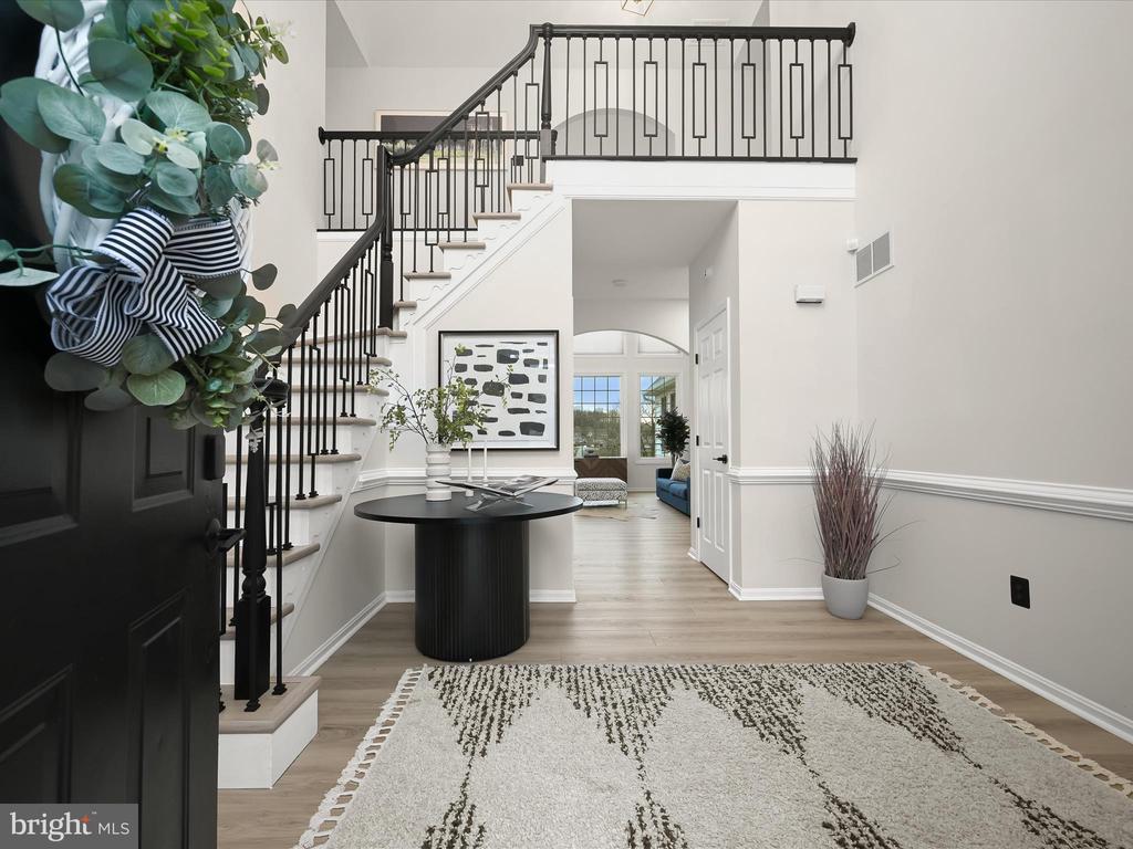 Two-story foyer with a black-railed staircase, round console table, and patterned rug.