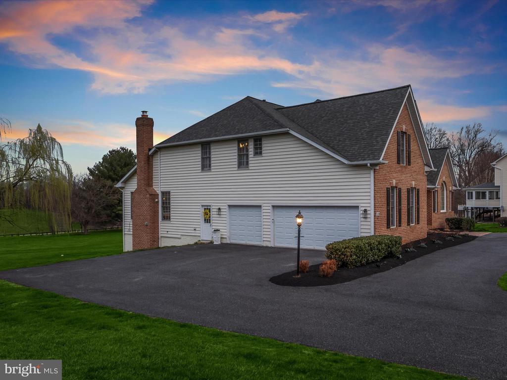 Two-story brick-and-siding home with a three-car garage and wide driveway at dusk.