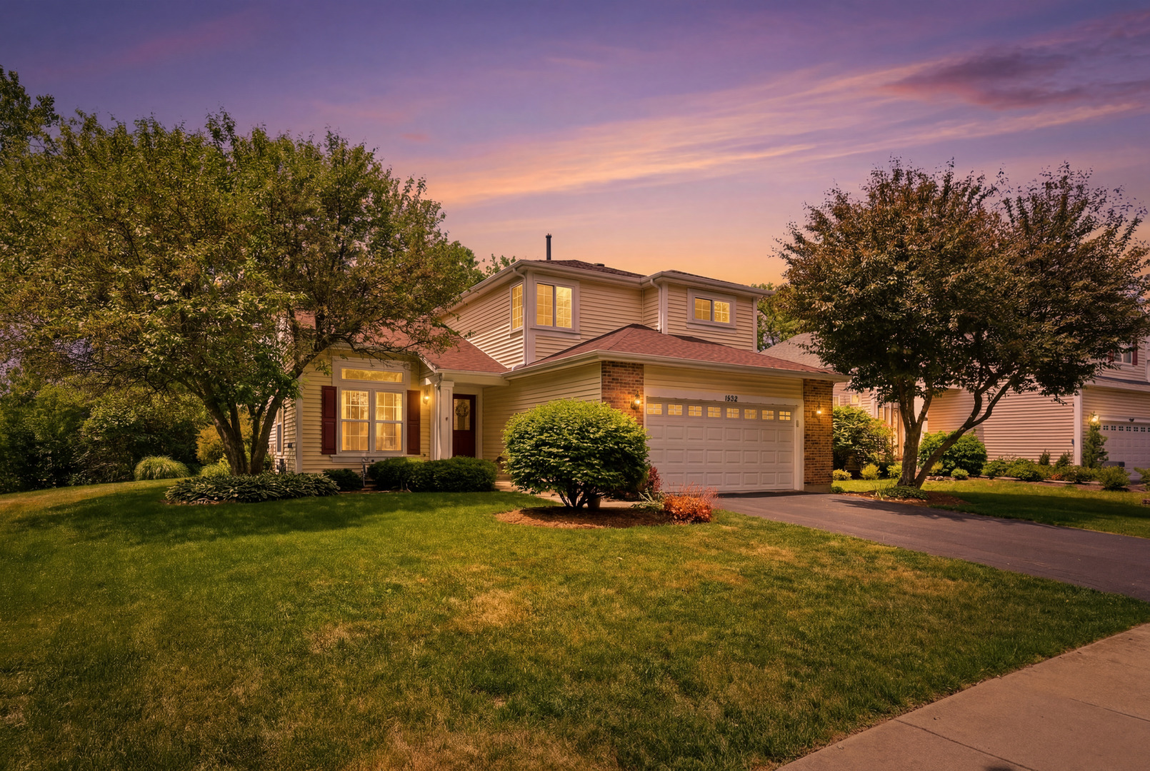Two-story suburban house with brick accents and a two-car garage at dusk.