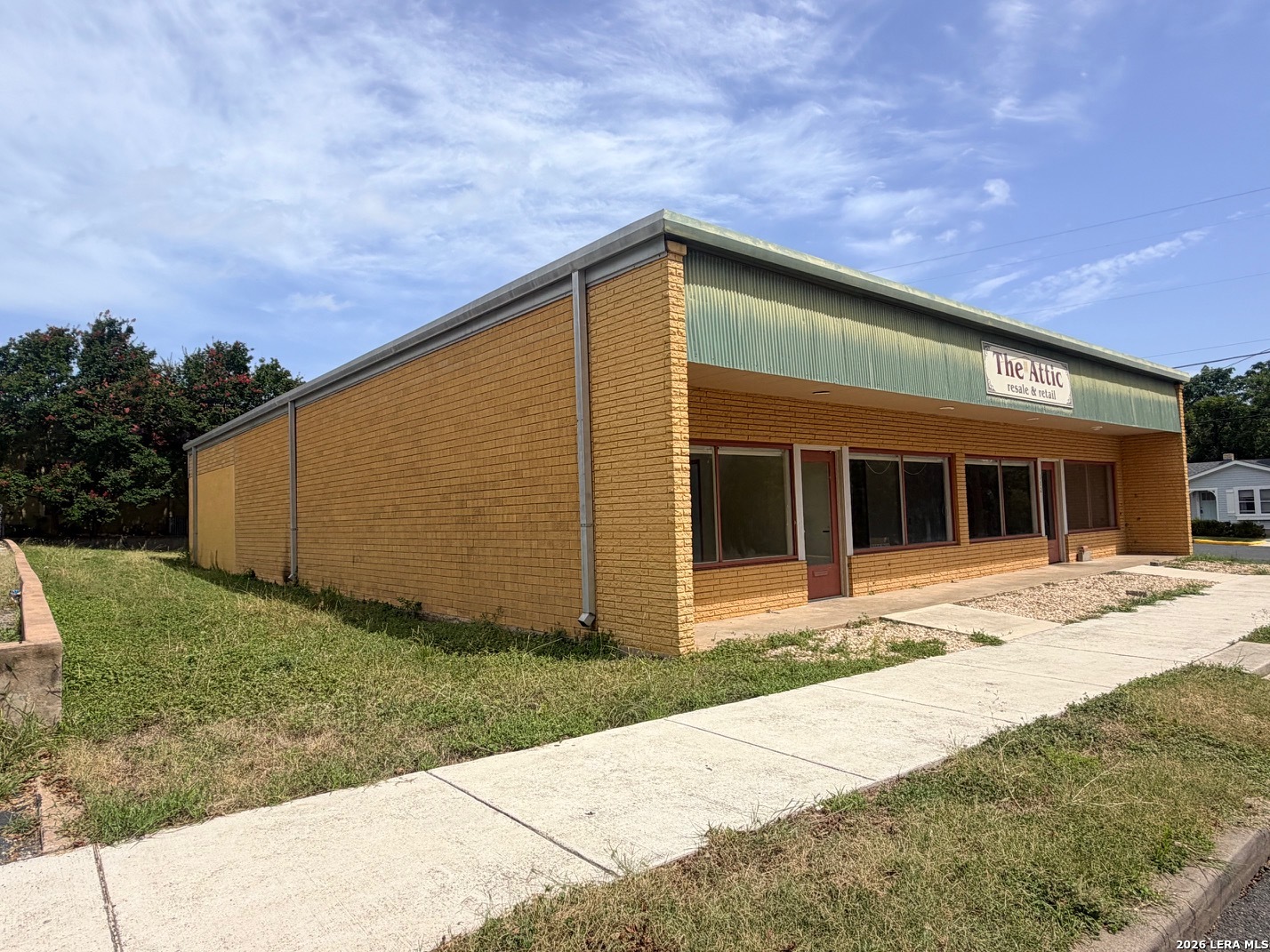 Yellow-brick storefront with green fascia and a sign for The Attic resale and retail.