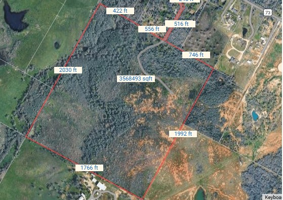 Aerial view of a wooded property parcel outlined in red with boundary measurements.