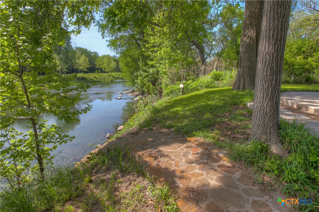 Wooded riverbank with a stone path leading down to the water.