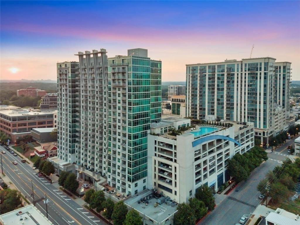 Aerial view of two condominium towers with a rooftop pool at sunset.